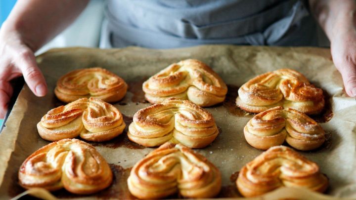 Goldene Hefegeb&auml;cke mit Muskatnuss werden frisch aus dem Ofen auf ein Backblech gelegt, bereit zum Servieren.