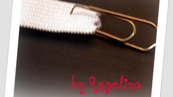 Ein wei&szlig;es Gummiband wird mit einer B&uuml;roklammer befestigt, w&auml;hrend sich der Hintergrund unscharf pr&auml;sentiert.