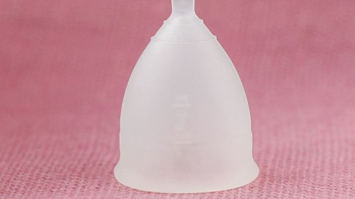 Eine Menstruationstasse steht auf einem rosa Hintergrund, symbolisiert kosteng&uuml;nstige Menstruationspflege und Nachhaltigkeit.