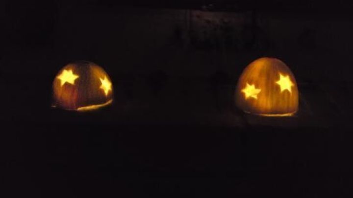 Zwei leuchtende Honigmeloneniglus mit Teelichtern strahlen durch den Schnee in der Dunkelheit, umgeben von winterlicher Stille.