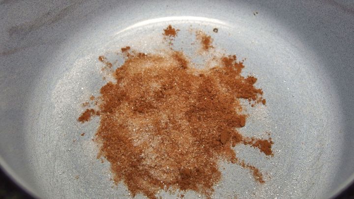 Zimt und Zucker liegen verstreut in einer wei&szlig;en Sch&uuml;ssel, um K&uuml;chenger&uuml;che zu entfernen und eine angenehme Atmosph&auml;re zu schaffen.