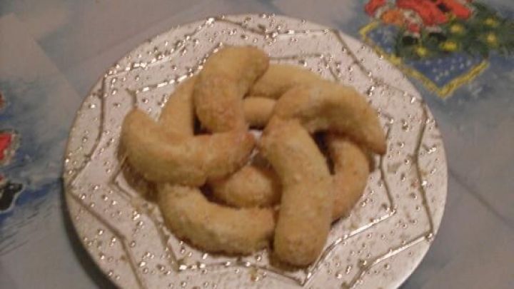 Kokoskipferl liegen auf einem dekorativen Teller auf einem Tisch mit festlichem Tischtuch.