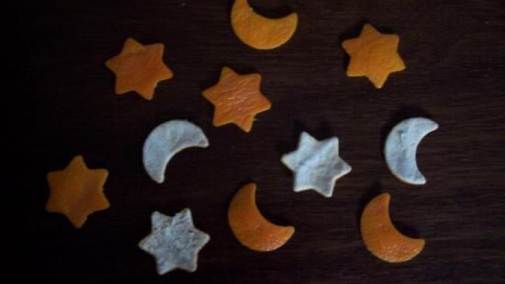 Mandarinscheiben sind kreativ zu Weihnachtsdeko geformt und liegen auf einem dunklen Tisch, um festliche Stimmung zu schaffen.