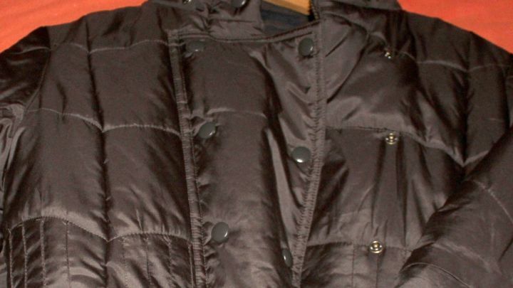 Eine schwarze Skijacke h&auml;ngt an einem Kleiderb&uuml;gel, bereit zum Waschen nach dem Skifahren.