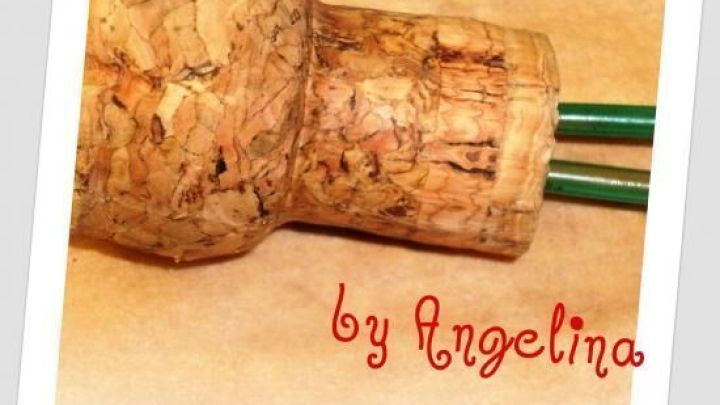 Ein Korken fungiert als Halter f&uuml;r Strickarbeiten, w&auml;hrend gr&uuml;ne Stricknadeln darin stecken. Der Hintergrund ist neutral.