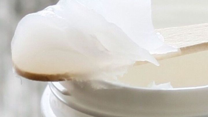 Vaseline in einem Beh&auml;lter, auf einem Holzspatel, bereit zum Schmieren auf einer knarrenden T&uuml;r in einem Innenraum.