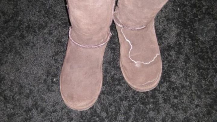 Zwei braune Wildleder-Stiefel stehen auf einem dunklen Teppich, bereit zur Reinigung von Salzr&auml;ndern mit Zwiebeln.