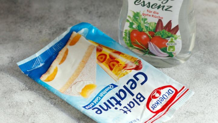 Essigflasche und Gelatinepackung liegen auf einer hellen Oberfl&auml;che, bereit zur Anwendung gegen Abflussprobleme.