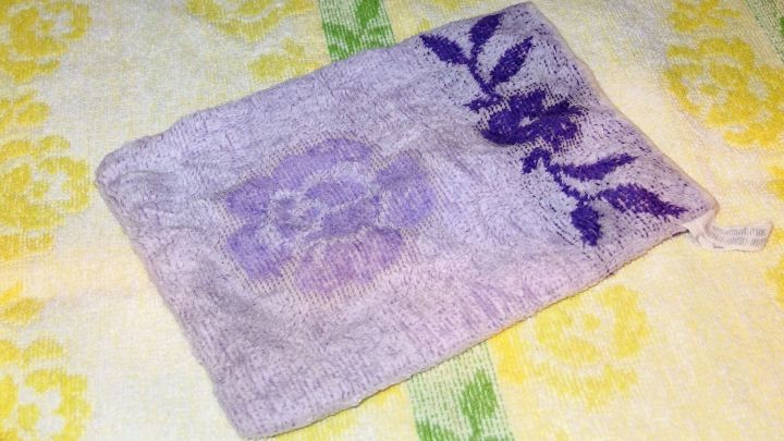 Ein kalter Waschlappen liegt auf einem gelben Handtuch und wird zur Linderung von Kopfschmerzen verwendet.