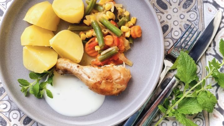 H&auml;hnchenschenkel aus dem Ofen auf buntem Gem&uuml;sebett mit Kartoffeln und Joghurtso&szlig;e &ndash; so wird dein Mittag besonders lecker