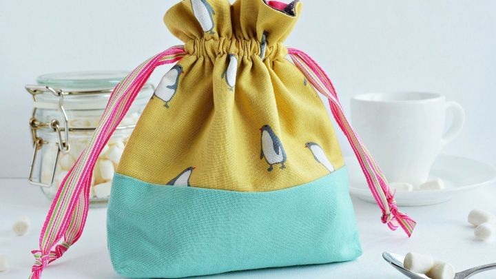 Ein farbenfrohes Stoffs&auml;ckchen steht auf einem Tisch, umgeben von einer Tasse und einem L&ouml;ffel mit Zucker.