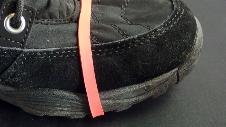 Schwarze, rutschfeste Schuhe mit einem Gummiband um den Fu&szlig;, bereit f&uuml;r den Gebrauch auf glatten Winteroberfl&auml;chen.