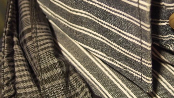 Ein gestreifter Kragen und ein kariertes Shirt liegen &uuml;bereinander, wobei der Kragenschmutz sichtbar ist.