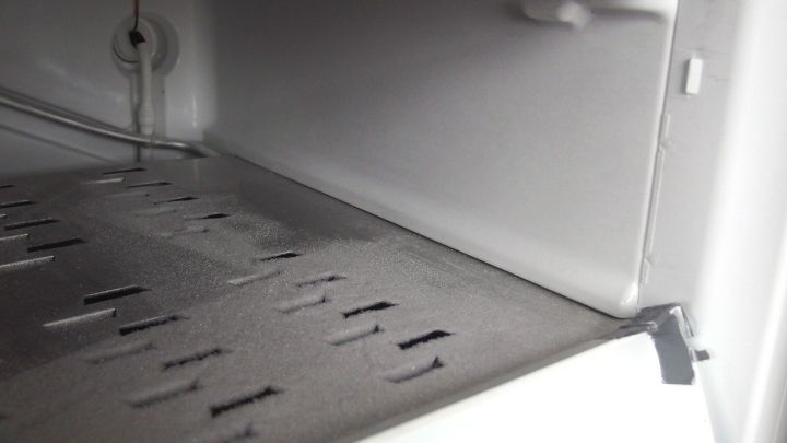 Ein Gefrierfach mit Eisablagerungen wird abgetaut, w&auml;hrend Wassertropfen sich am Boden sammeln.