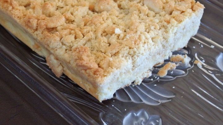 Ein Streuselkuchen liegt auf einem wei&szlig;en Teller. Ein St&uuml;ck ist bereits herausgenommen. Der Kuchen hat eine goldbraune, knusprige Streuselschicht.