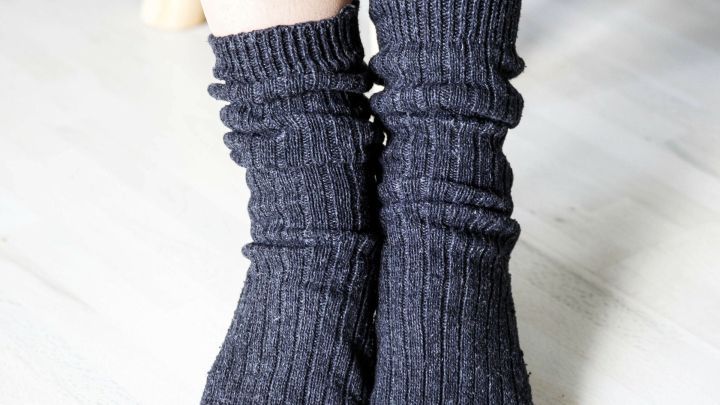 Dunkelgraue Wollsocken umschlie&szlig;en die F&uuml;&szlig;e und bieten Komfort auf einem hellen, neutralen Boden.