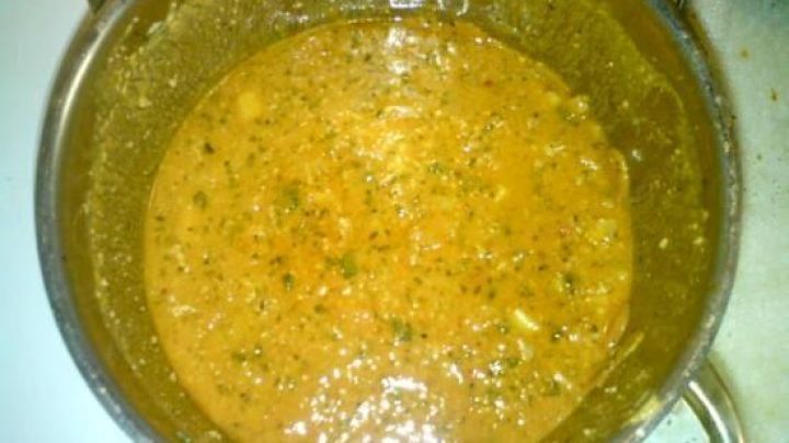 Ein gro&szlig;er Topf mit Gem&uuml;seeintopf kocht auf dem Herd, umgeben von einer neutralen K&uuml;cheneinrichtung. Der Eintopf enth&auml;lt Gem&uuml;se und Gew&uuml;rze.