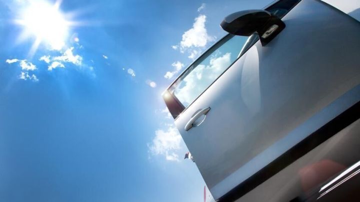 Ein silbernes Auto steht unter einem strahlend blauen Himmel, w&auml;hrend jemand sich auf das Aussteigen vorbereitet, um Stromschl&auml;ge zu vermeiden.