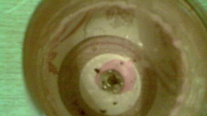 Ein leeres Kerzenglas steht auf einem Tisch und zeigt Reste der Kerze im Inneren, umgeben von einem unauff&auml;lligen Hintergrund.