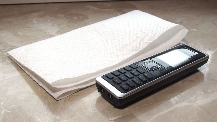 Ein Telefon liegt auf einem Tisch neben einem Stapel Papiert&uuml;cher, bereit f&uuml;r das Telefonieren mit Teigh&auml;nden.