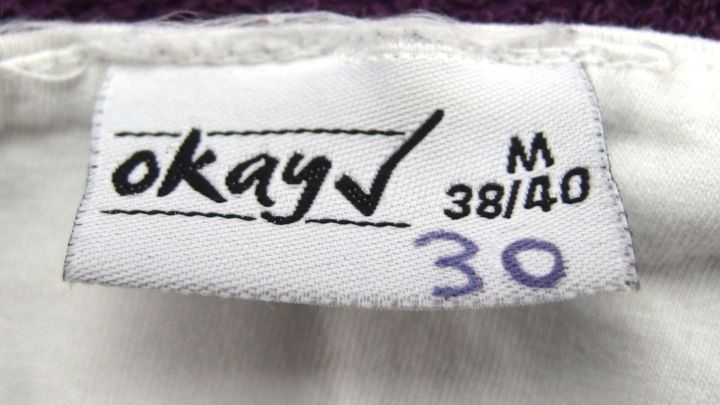 Ein W&auml;scheetikett zeigt die Markierung "30", w&auml;hrend es an einem Kleidungsst&uuml;ck h&auml;ngt, um die Waschtemperatur zu kennzeichnen.