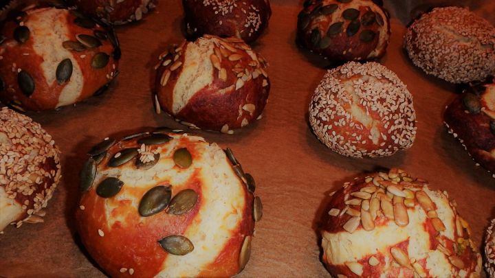 Leckere Laugengeb&auml;cke liegen auf einem Tisch, frisch gebacken und mit verschiedenen Toppings bestreut.