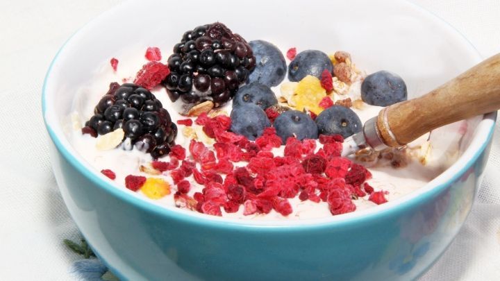 Eine Sch&uuml;ssel M&uuml;sli mit frischen Beeren und knusprigen Toppings steht auf einem Tisch, bereit zum Genie&szlig;en.
