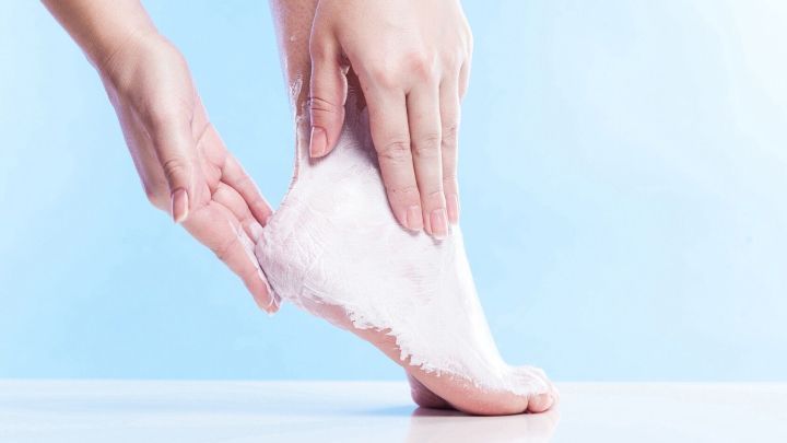 Eine Hand tr&auml;gt Erk&auml;ltungsbalsam auf einen Fu&szlig; auf; Hintergrund ist ein hellblauer Farbverlauf.