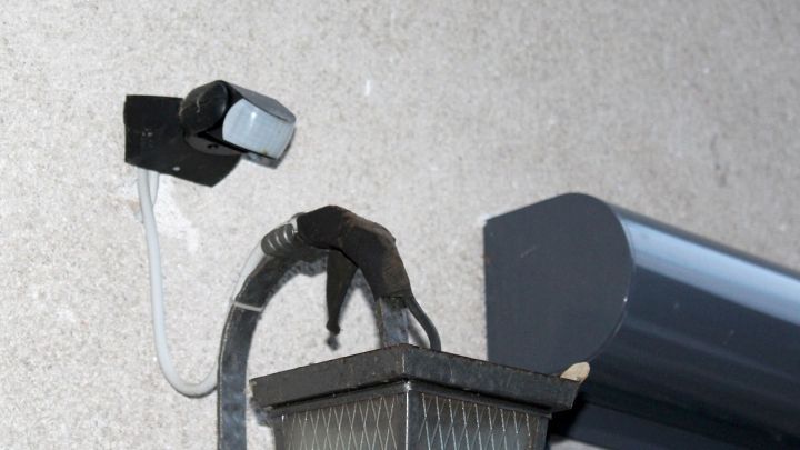 Ein Bewegungsmelder ist an einer Wand montiert, w&auml;hrend er darauf wartet, Tauben von einer Lampe zu vertreiben.