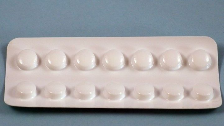 Eine Tablettenblisterpackung zeigt mehrere rundliche Tabletten, die zum Einnehmen bereitliegen auf einem einfarbigen Hintergrund.