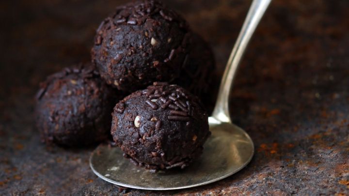 Dunkle Schokoladenkugeln liegen auf einem L&ouml;ffel, umgeben von einer rustikalen, metallischen Oberfl&auml;che.