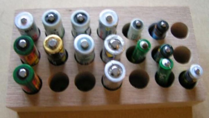 Eine Reihe von Akkus steht ordentlich in einem Holzeinsatz, der sie sicher aufbewahrt und organisiert.