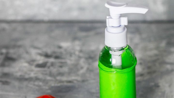 Eine gr&uuml;ne Flasche mit Pumpkopf steht neben einem roten Luftballon, der zum Schutz der Flasche verwendet wird.