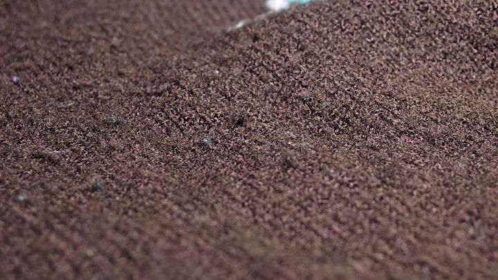 Ein brauner Wollpullover zeigt feine Knoten, die mithilfe einer Kleiderb&uuml;rste sanft entfernt werden.