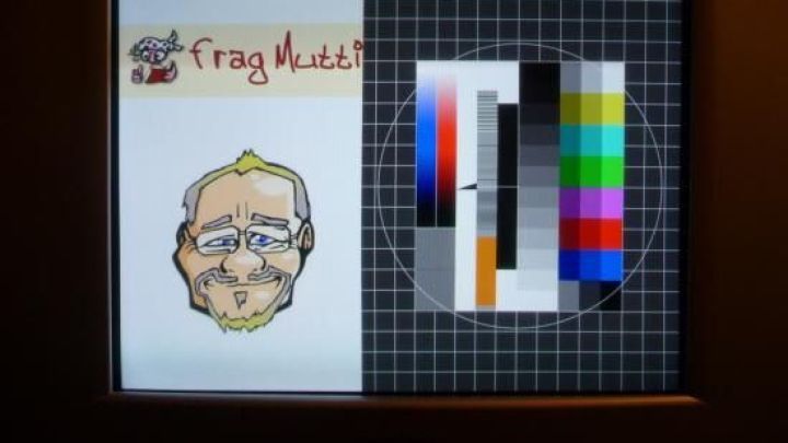 Ein Bildschirm zeigt links eine gezeichnete M&auml;nnerfigur mit dem Text &bdquo;Frag mich!&ldquo;, rechts Farbkarten f&uuml;r die Kalibrierung.