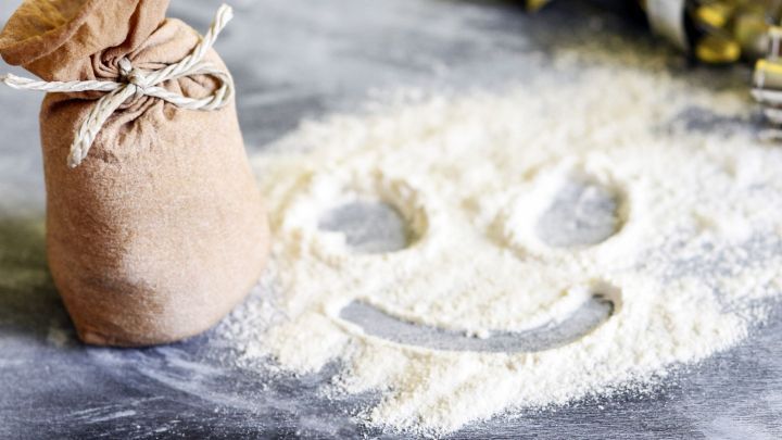 Ein gef&uuml;llter Nylonstrumpf liegt neben einer Menge Mehl, in das ein l&auml;chelndes Gesicht gezeichnet ist.