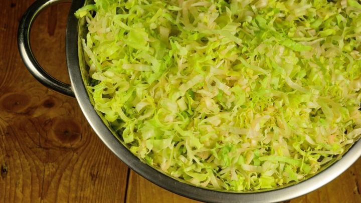 Ein Sieb h&auml;lt fein geschnittenen Endiviensalat auf einem Holztisch.