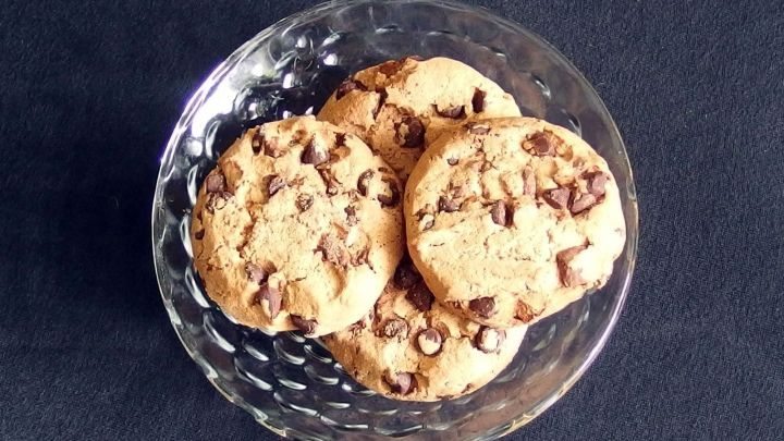 Schokoladenkekse liegen in einer klaren Sch&uuml;ssel auf einem dunklen Untergrund und laden zum Genie&szlig;en ein &ndash; backen ohne Ei.