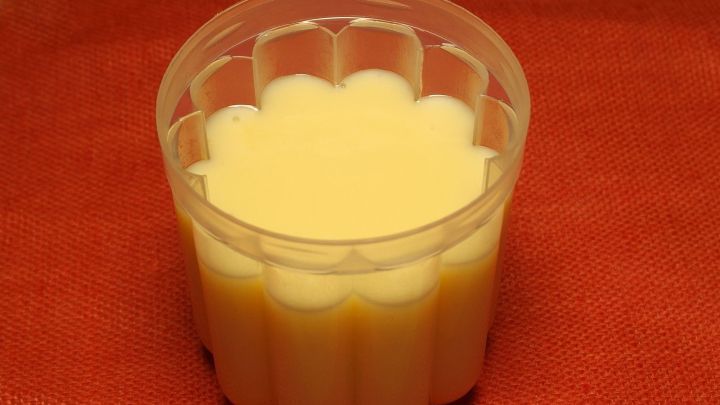 Ein gelber Beschwippster Pudding steht in einer Form auf einem roten Hintergrund und wartet darauf, serviert zu werden.