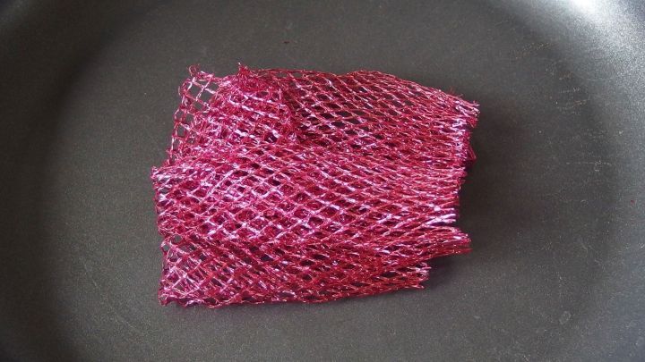 Ein rosafarbener K&uuml;chenschwamm liegt auf einer Pfanne und ist bereit, T&ouml;pfe und Pfannen zu reinigen.