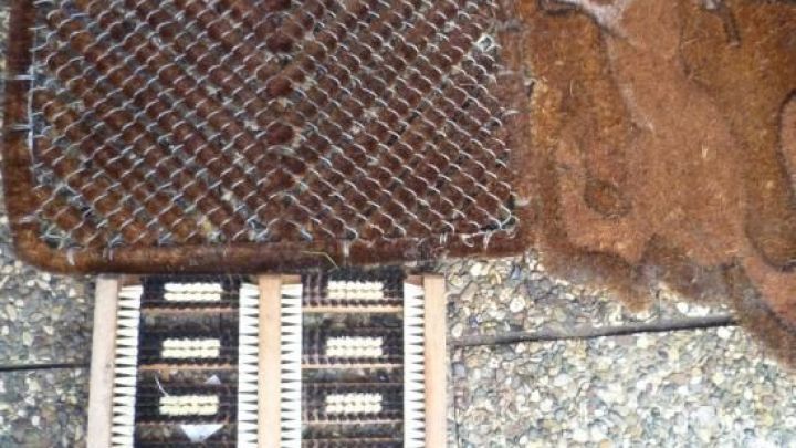 Eine schmutzige Fu&szlig;matte liegt auf einem Gehweg, w&auml;hrend eine K&auml;rcher-Reinigungsmaschine sie s&auml;ubert.