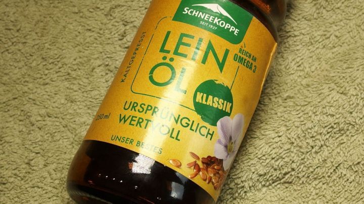 Ein Flasche Lein&ouml;l steht auf einem gr&uuml;nen Tuch. Sie ist beschriftet mit &bdquo;LEIN&Ouml;L UNSP&Auml;NGLICH WERTVOLL&ldquo;.