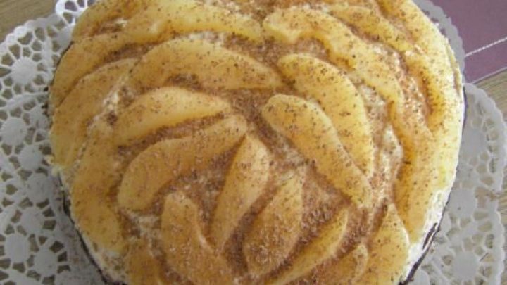 Herzf&ouml;mige Birnensahnetorte auf Spitze, garniert mit Mandeln, arrangiert auf lilafarbenem Tischtuch.