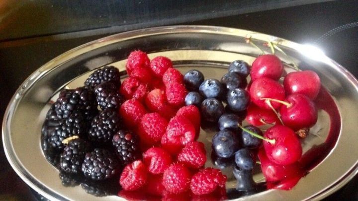 Eine silberne Platte mit einer bunten Mischung aus Beerenobst: Himbeeren, Heidelbeeren, Brombeeren und Kirschen.