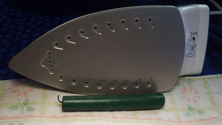 Ein B&uuml;geleisen liegt auf einem Tisch, neben einem gr&uuml;nen Reinigungsstift, bereit zum Reinigen.