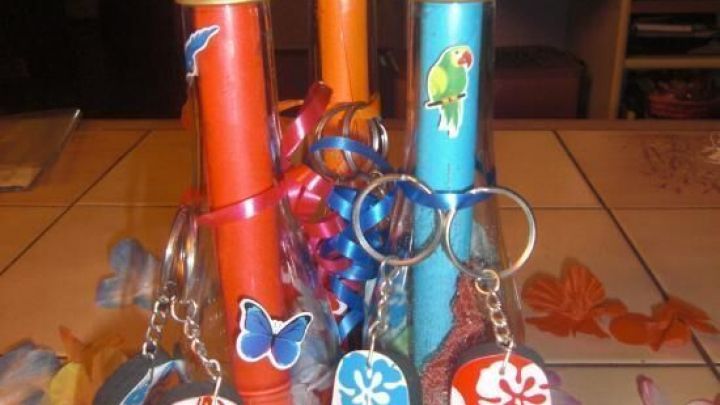 Bunte Flaschenpostrollen stehen in einer Gruppe, umgeben von sommerlichen Accessoires. Schl&uuml;sselanh&auml;nger in Flip-Flop-Form h&auml;ngen daneben.