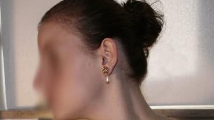 Ein Haarspray wird verwendet, um einen strengen Knoten zu fixieren, w&auml;hrend sich die Person in einem hellen Raum befindet.