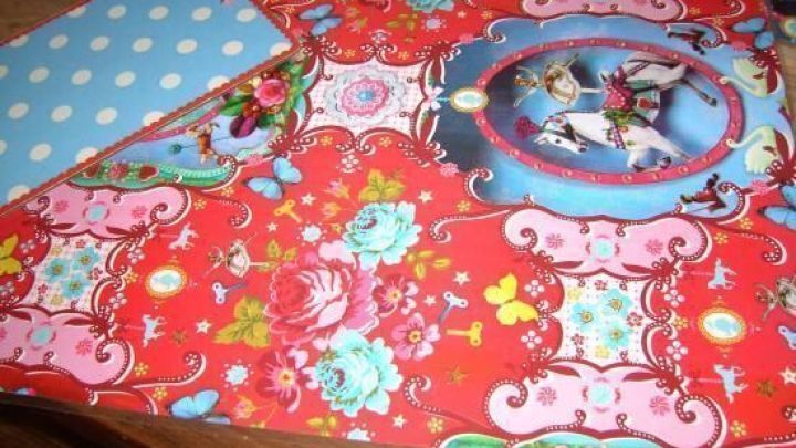 Bunte Tischsets mit floralen Mustern und einem blauen Polka-Dot-Rand liegen kreativ auf einem Holztisch.