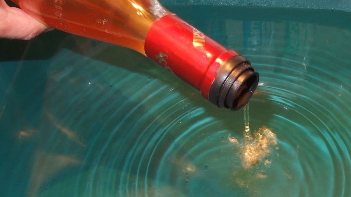 Eine Flasche Essig wird &uuml;ber eine gr&uuml;ne Sch&uuml;ssel gekippt, w&auml;hrend Fl&uuml;ssigkeit ins Wasser flie&szlig;t.