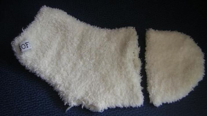 Ein zerlegter wei&szlig;er Socken liegt auf dunklem Hintergrund. Ein Teil des Socken hat ein Etikett mit der Aufschrift "OF".
